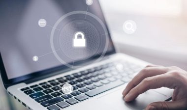 Close up of a mans hand using a laptop with a data security overlay. Data breach concept.
