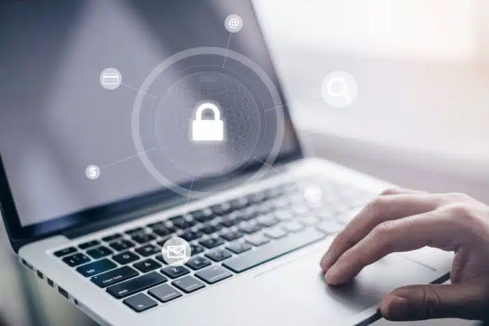 Close up of a mans hand using a laptop with a data security overlay. Data breach concept. - Sea Mar Community Health Centers data breach class action lawsuit settlement