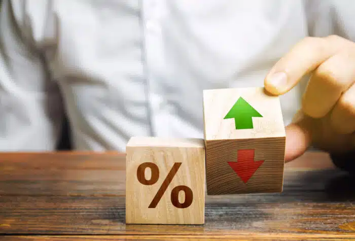 Businessman holds wooden blocks with percent and up or down arrow.