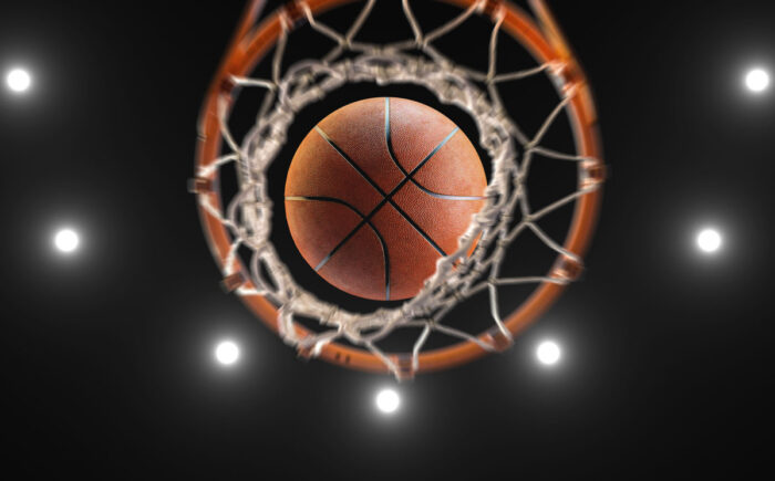 Bottom view of a basketball going through a basketball hoop.