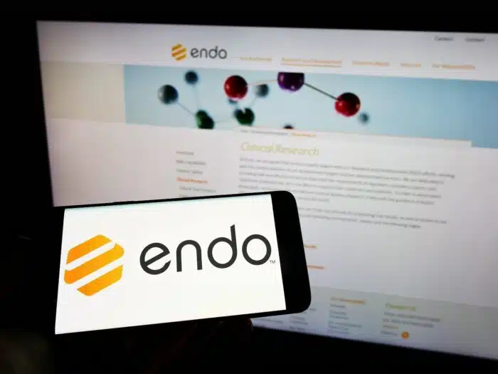 phone with logo of pharmaceutical company Endo International plc on screen in front of web page - Opana ER, Impax, opana class action