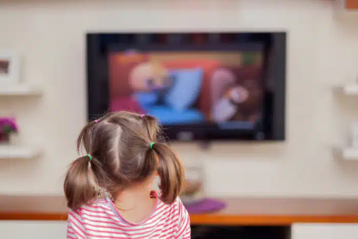 Back view of a young girl watching TV.