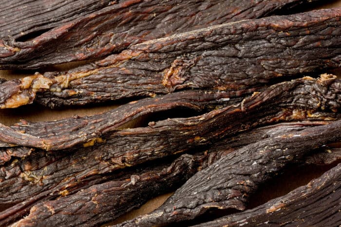 Background texture of several pieces of black pepper beef jerky.