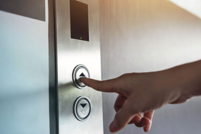 Close up of a hand pushing an elevator button.