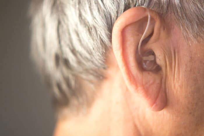 Close up of a hearing aid in an elderly womans ear - Beltone warranty
