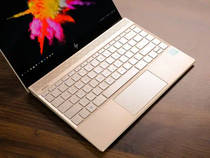 Close up of an open HP laptop on a wooden table.