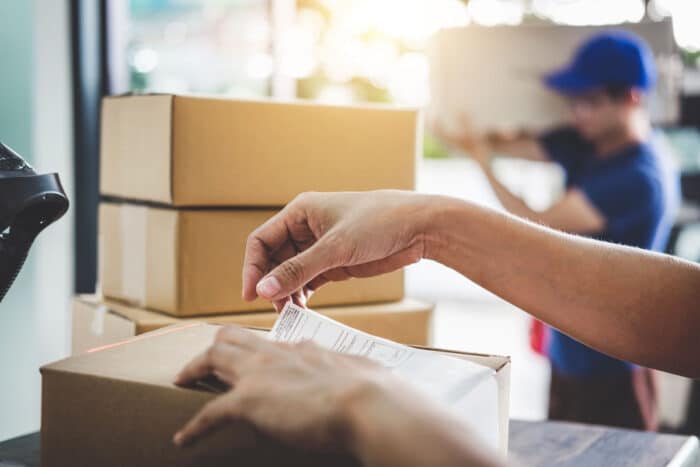 Close up of a workers hand preparing a package for delivery - Echo Global Logistics employees