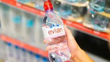 Close up of a hand holding an Evian water, representing the Evian class action.