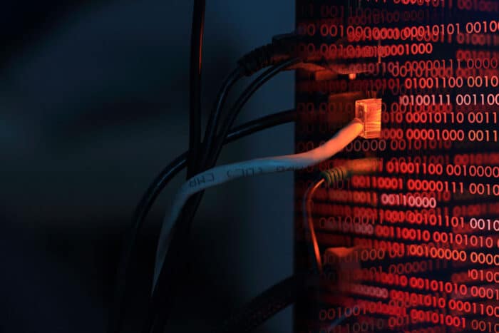 Close up of cables plugged into computer tower with binary code overlay. Data breach concept. United Health Centers of San Joaquin Valley