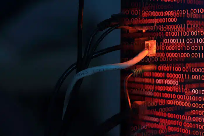 Close up of cables plugged into computer tower with binary code overlay. Data breach concept. United Health Centers of San Joaquin Valley