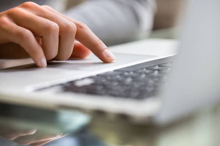 Close up of a womans hands using a laptop.