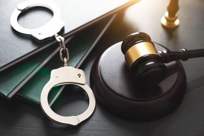 Handcuffs and wooden gavel resting on law books on a desk, representing Santa Clara County jail wrongful detention settlement.