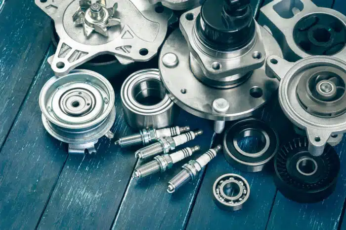 Close up of various car parts on a wooden table - auto parts class action settlement