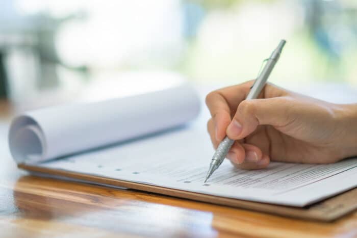 Hand with pen over loan application form.