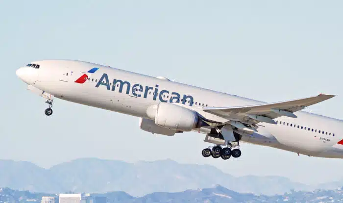 American Airlines plane taking off against a bright blue sky.