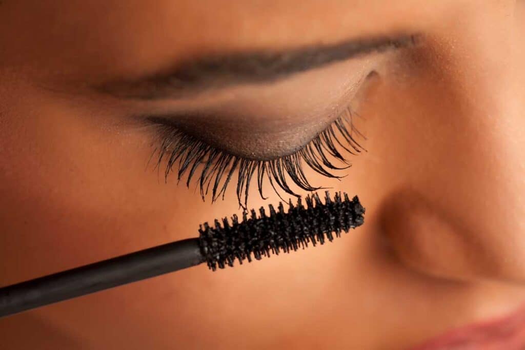 Close up of young woman putting on mascara - PUR mascara PFAS
