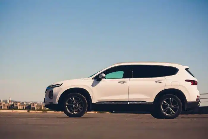 Side view of a white 2018 Hyundai Santa Fe against a blue sky.