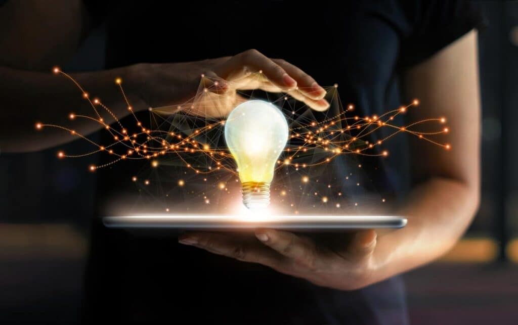 Hands holding tablet with light bulb future technologies and network connection on virtual interface background, representing the InventHelp class action settlement - Invention Submission Corp.