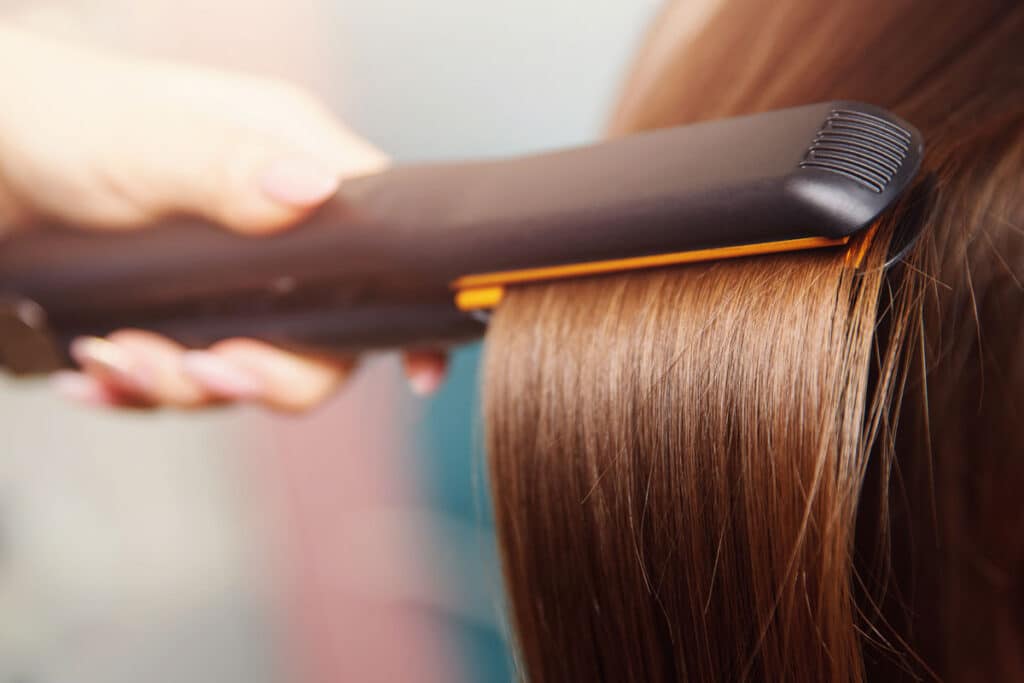 Close up of a hair straightener straightening hair.