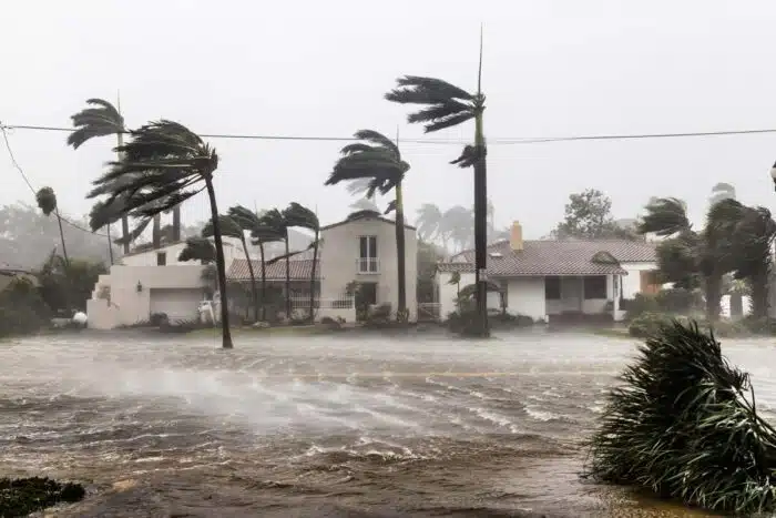 A flooded street during a hurricane with damage homes in the background. The Make It Right Foundation has agreed to a class action settlement.