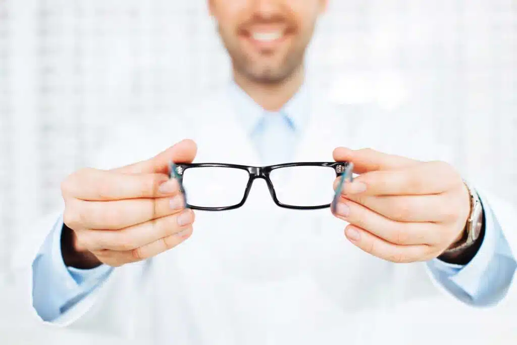 Closeup of optician, optometrist giving eyeglasses to try.