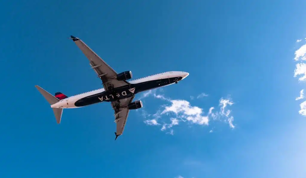 Delta Airlines airliner is flying in sky on sunny day.