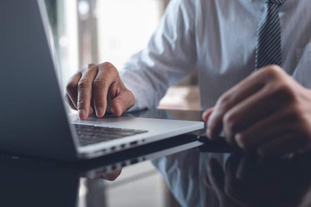 Close up of a mans hands using a laptop computer.