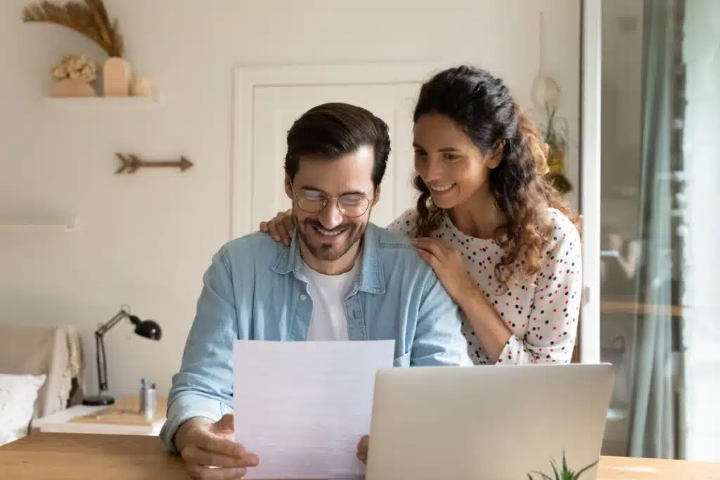 Happy young wife embrace shoulders of beloved husband reading notice of refund, representing the Riverside Public Utilities general fund fees refund.