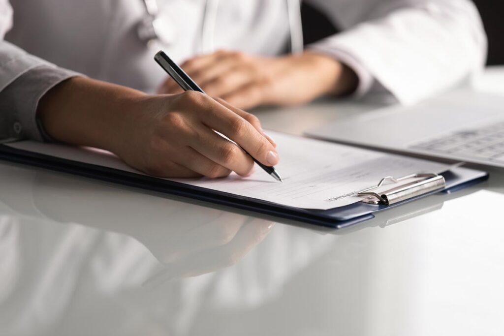 Close up of a pharmacists hands holding a pen while taking an exam.