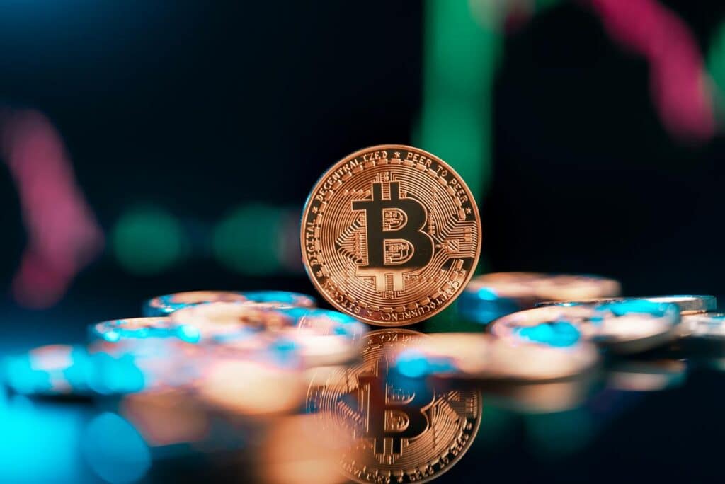 Bitcoin cryptocurrency with colorfull blurred candlestick chart in the background.