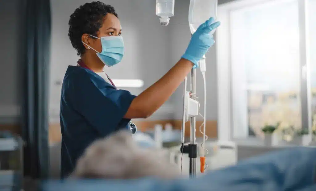 A nurse in a hospital preparing an IV drip, representing the CommonSpirit Health nurse class action lawsuit settlement.