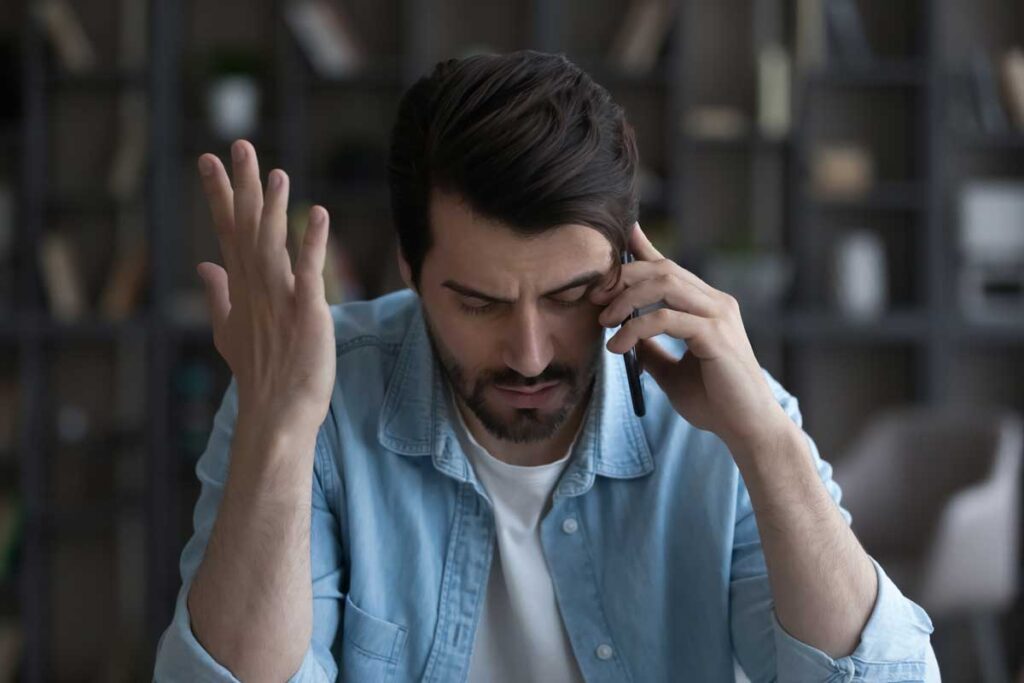 Close up of a frustrated young man on the phone, representing the Bath Saver spam calls lawsuit settlement.