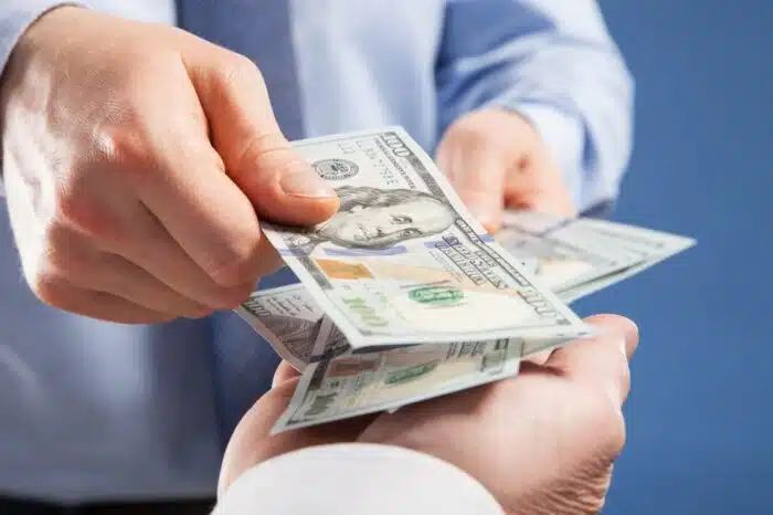 hands exchanging money on blue background, representing FTC payments.