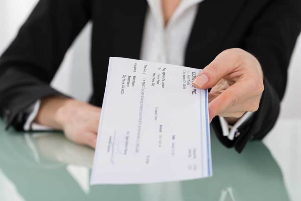 Close up of a womans hands giving a paper paycheck, representing the Portfolio Recovery Associates settlement.