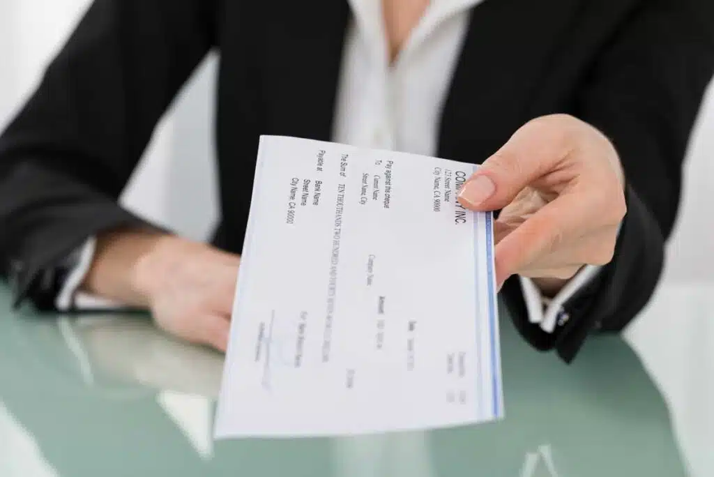 Close up of a womans hands giving a paper paycheck, representing the Portfolio Recovery Associates settlement.