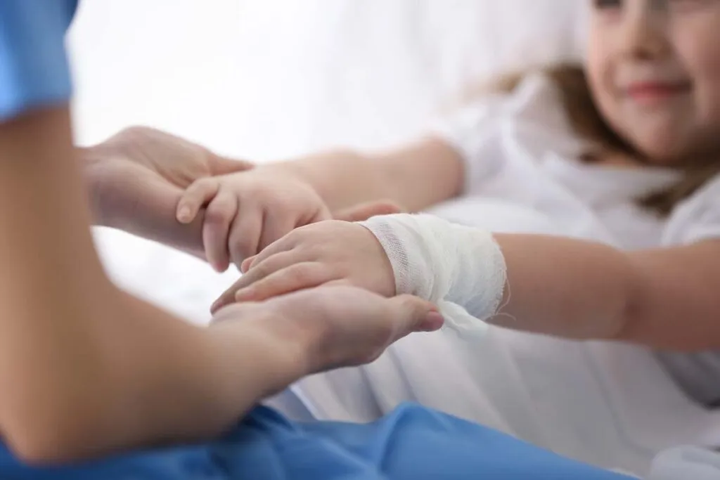 Closeup of doctor holding girl's hands in hospital, representing the Lurie Children’s Hospital medical records data breaches settlement.