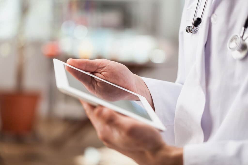 Close up of a doctors hands using a digital tablet, representing the San Juan Medical Center settlement, sjrmc claims.