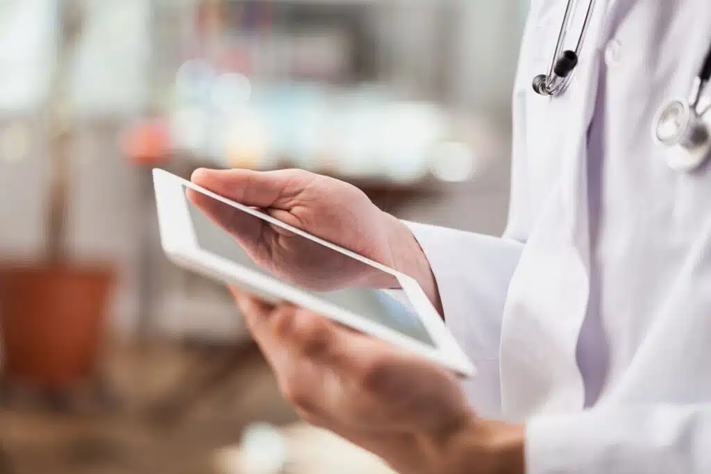 Close up of a doctors hands using a digital tablet, representing the San Juan Medical Center settlement, sjrmc claims.