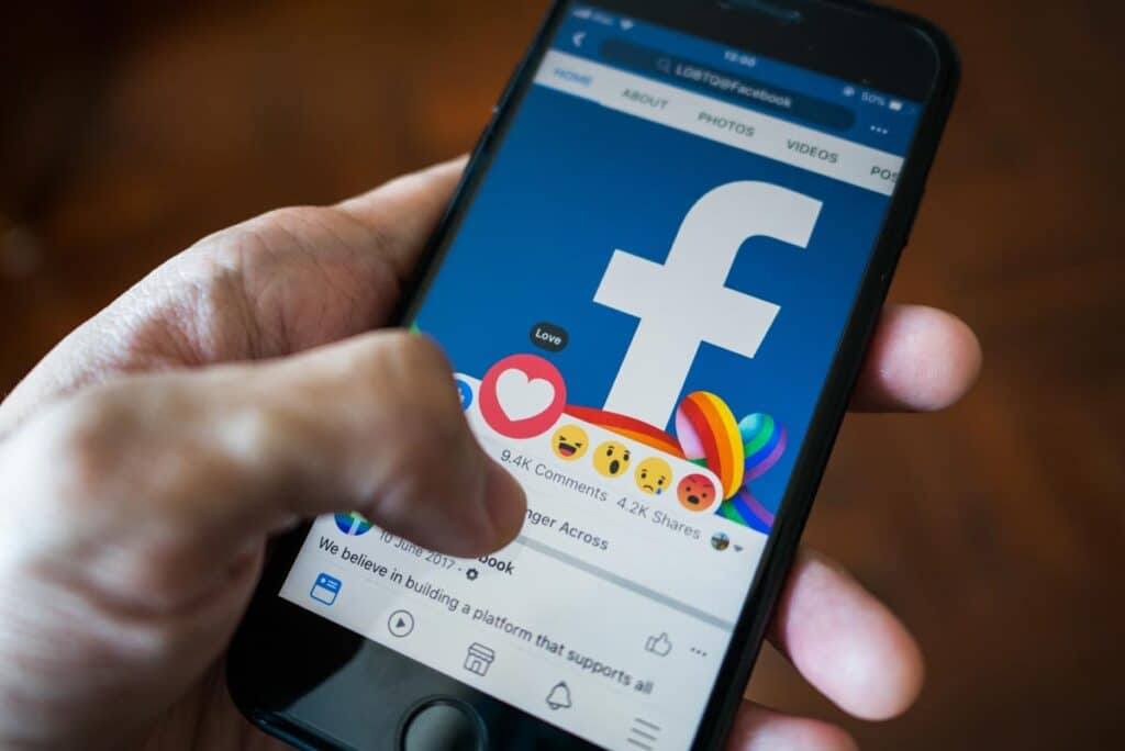Close up of a person using a smartphone to react to a post on Facebook.