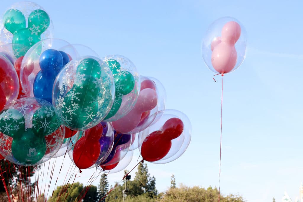 Colorful Disney shaped balloons against a blue sky.