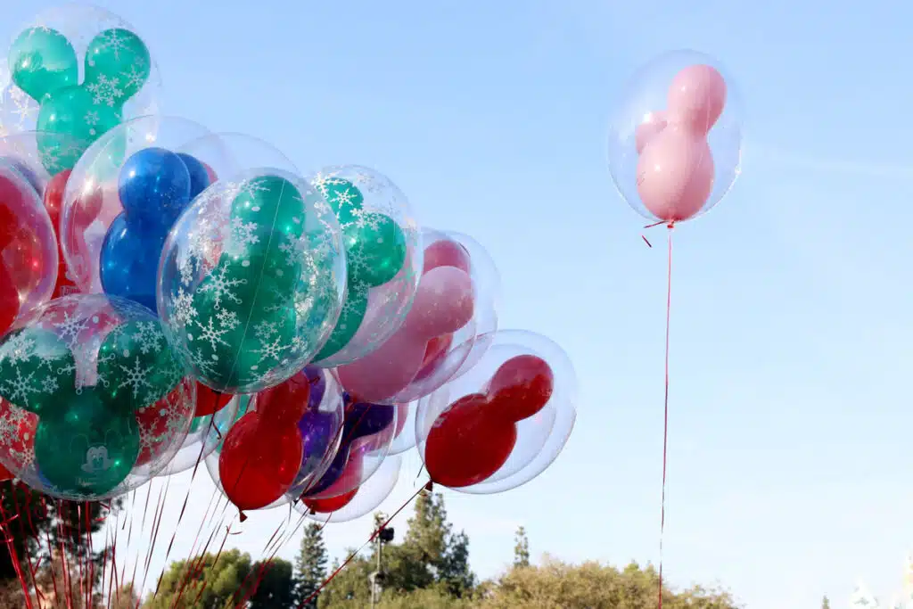 Colorful Disney shaped balloons against a blue sky.
