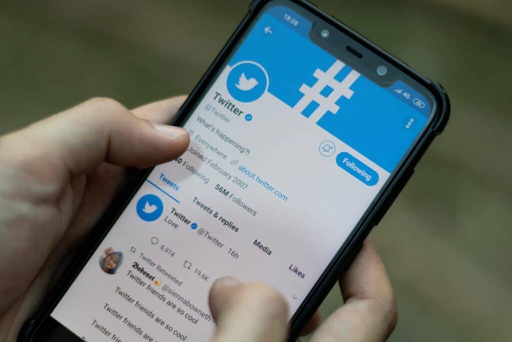 Close up of hands holding a smartphone and using Twitter application.