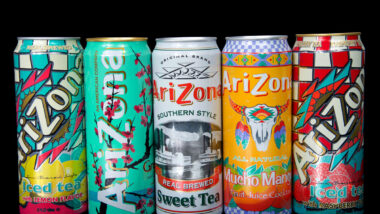 Cans of Arizona brand ice teas in various flavors isolated against a black background.