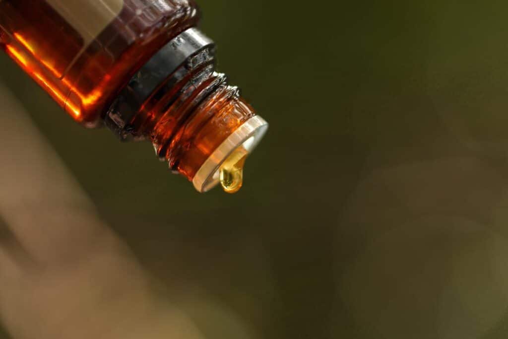 Essential oil bottle close up with drop of oil forming.