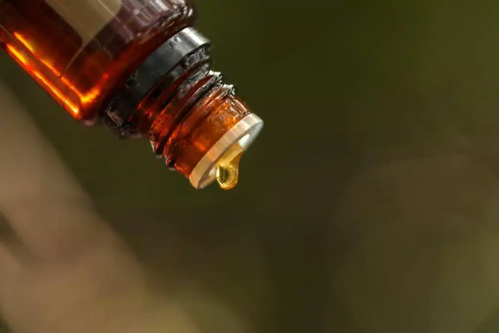 Essential oil bottle close up with drop of oil forming.
