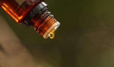 Essential oil bottle close up with drop of oil forming.