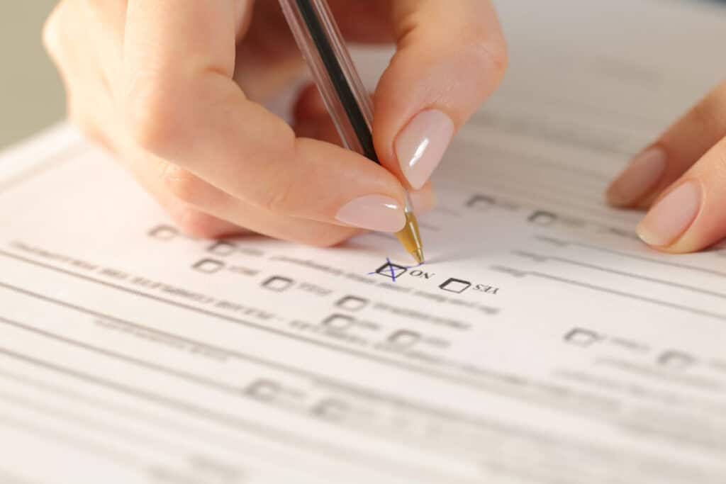 Close up of a females hands filling out a religious exemption form.