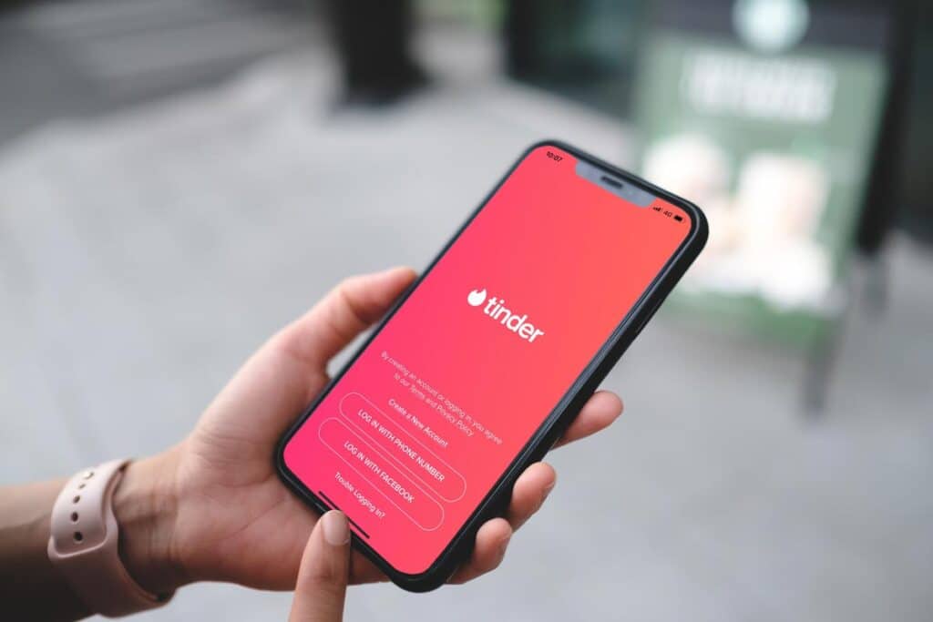 Tinder application icon on Apple iPhone X screen close-up.
