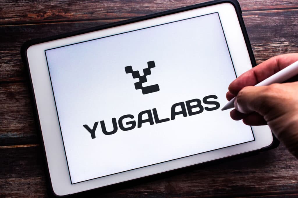 Close up of Yuga Labs logo displayed on an iPad against a wood background.