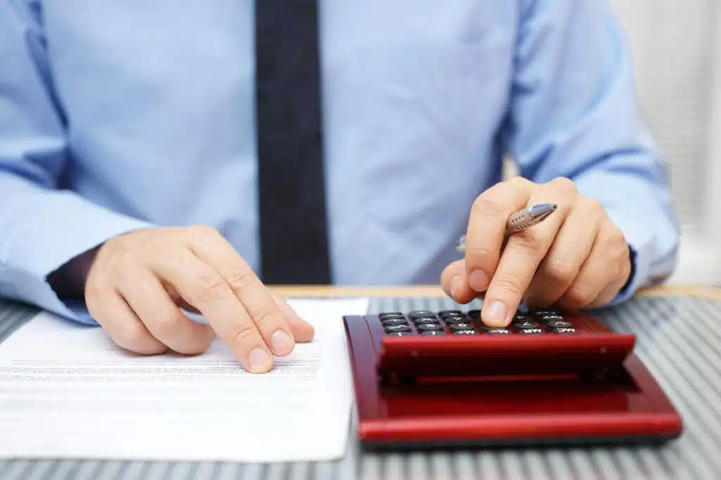 Close up of a businessman using a calculator to calculate fees, representing the CFLA fees settlement.